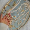 Person Holding a Pearl Necklace on Silver Tray